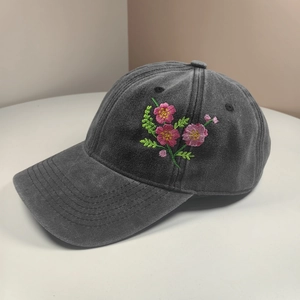 Detailed close-up of pink flower embroidery on a charcoal grey washed cotton baseball cap
