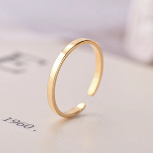 Macro shot of minimalist open gold ring showing polished metallic texture and adjustable band