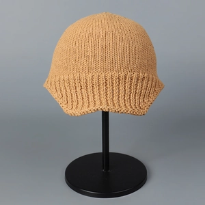 Front view of a yellow knitted breathable peak cap on a black display stand