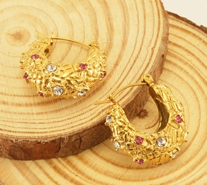 Detail of 18K gold plated woven earrings with pink and white rhinestones on wood