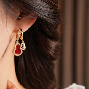 Close-up of gold-plated red agate gourd earrings with pavé zircon stones on a model