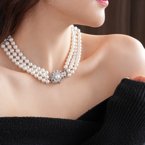 Elegant multi-strand pearl necklace with floral rhinestone clasp on female model