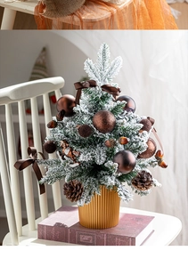 Mini Christmas tree with pine cones and golden ornaments on a white chair in home setting