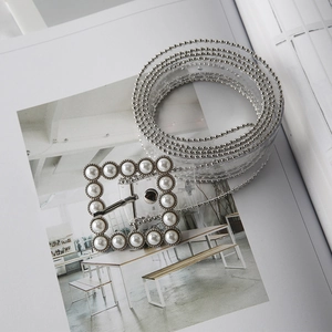 Detail of transparent PVC belt featuring a square buckle with white pearls and silver beaded edges