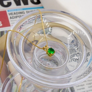 Minimalist gold titanium necklace with a round emerald green zircon pendant in four-prong setting
