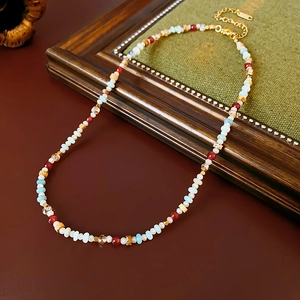 Macro detail of a colorful beaded necklace with gold clasp on a vintage wood surface