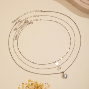 Detailed view of silver layered necklace set with heart and round disc pendants