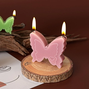 Pink 3D butterfly scented candle with dual wicks on a natural wood base, textured wings