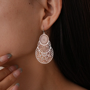 Gros plan de la boucle d'oreille fleur argentée évidée avec texture métallique sur modèle