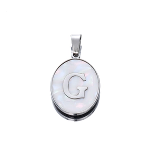 Macro shot of oval stainless steel pendant with letter G and mother of pearl inlay