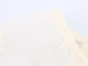 Gros plan détaillé du tissu beige clair avec broderie fine et finitions de l'ourlet
