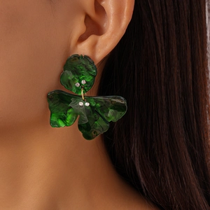 Macro shot of green leaf resin earrings with small crystals on model ear