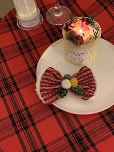 Close-up of a festive red Christmas bow headband with soft white fur and colorful pom-poms