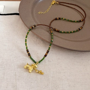 Detail of vintage gold plated tiger eye horse pendant necklace on ceramic plate