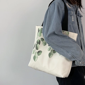 Model wearing a minimalist canvas tote bag with green eucalyptus leaf print detail
