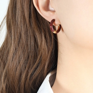Vintage style gold and dark red enamel titanium steel round earrings worn by a model