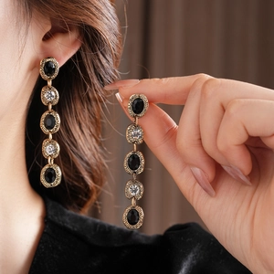 Détail de boucles d'oreilles vintage avec pierres ovales noires et pampilles dorées
