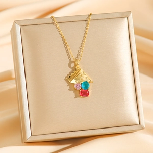 Collier en titane doré avec pierres colorées posé sur boîte cadeau et tissu en soie
