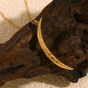 Detailed view of an 18K gold crescent moon necklace pendant with a textured finish