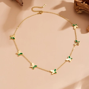 Dettaglio della collana farfalla dorata con zirconi verdi su decorazione in legno