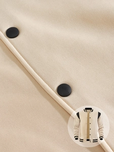 Close-up of beige varsity jacket fabric texture with black matte metal snap buttons