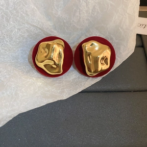 Detail of red velvet heart earrings with irregular golden liquid metal accents