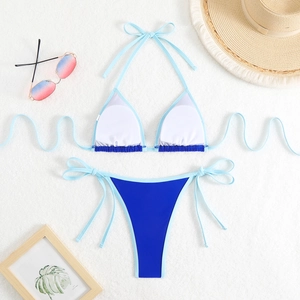 Two-piece color block bikini set with halter top and side tie bottoms on beach accessories