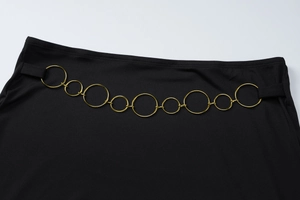 Détail de la taille d'une robe noire courte avec une ceinture à anneaux en métal doré