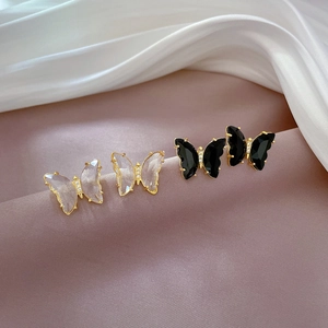 Macro detail of butterfly earrings with crystal wings on purple silk fabric