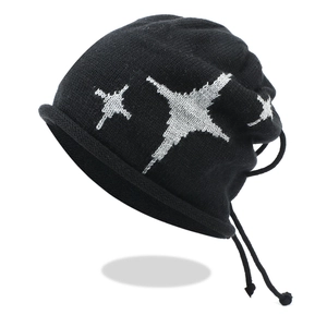 Close-up of black knit beanie featuring silver star patterns and decorative drawstrings