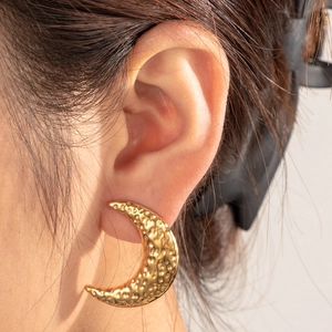 Elegant gold crescent moon earrings with textured hammered finish on model view