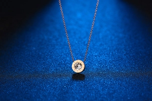 Macro shot of rose gold necklace pendant with white crystal and Roman numerals detail