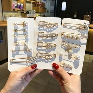 Close-up of gold-plated metal brooches with pearls and sparkling rhinestones