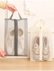 Detail of travel shoe bags with mesh windows, zippers, and handles in gray and cream