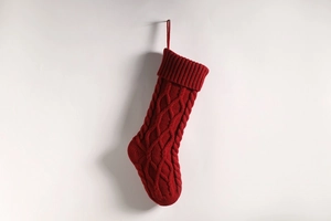 Close-up of a red cable-knit Christmas stocking with ribbed cuff on a white background