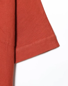Détail de la couture et texture du lin sur le poignet de la robe tunique rouge brique