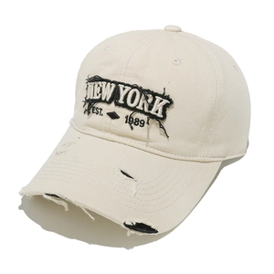 Detailed view of frayed NEW YORK embroidery and distressed vintage details on beige cap