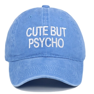 Close-up of 'CUTE BUT PSYCHO' white embroidery on washed blue cotton baseball cap