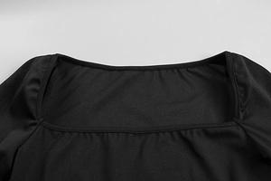 Detail of square neckline and fine stitching on a slim-fit black knit dress