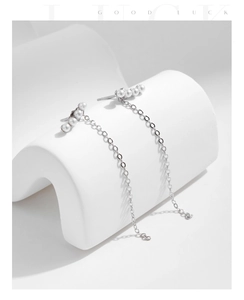 Close-up of s925 silver long chain tassel earrings with four white pearls and sleek metal finish