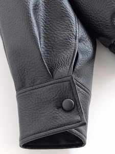 Gros plan du poignet d'une veste en similicuir noir avec coutures fines et texture grainée