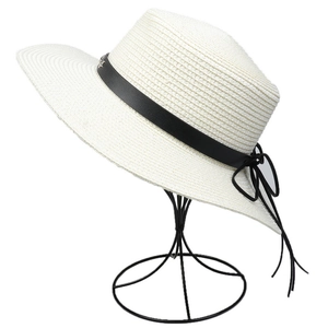 Detail of off-white straw sun hat featuring a black decorative band and metal buckle
