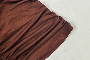 Detail of ruched stitching and elastic texture on brown bodycon dress fabric