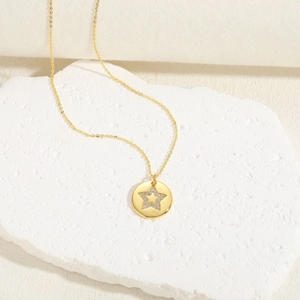 Macro shot of 14K gold plated necklace with zircon star disc pendant on white stone