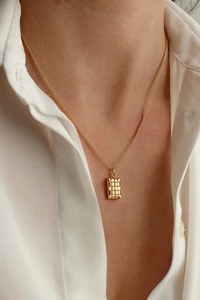 Detailed close-up of a gold star and moon rectangular pendant necklace on a model neck