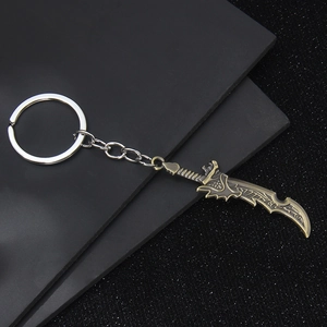 Bronze metal scimitar keychain with intricate carvings on dark textured background