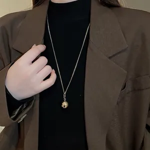 Minimalist golden ball pendant necklace shown on a model with a black turtleneck