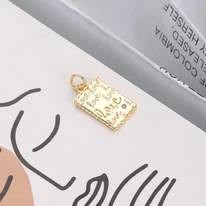 Close-up of a wavy rectangular gold pendant engraved with love and a small zircon stone