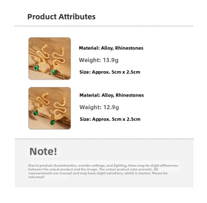 Detail of gold snake earrings with green pear-shaped crystal on wooden texture background