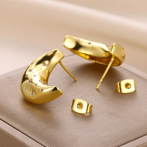 Macro shot of gold crescent moon studs with sparkling white zircons on a jewelry box